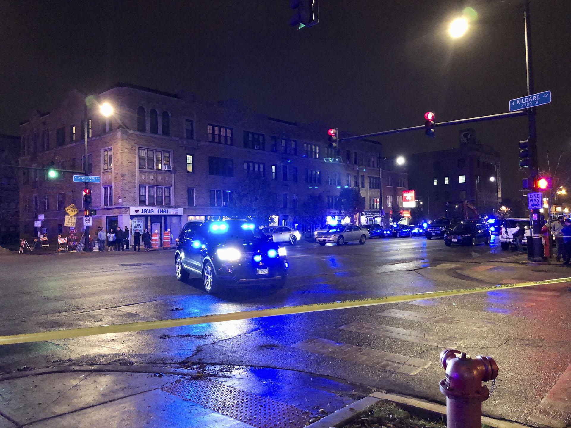 Chicago Police investigate the scene where an officer was shot by a suspected bank robber in Chicago, Tuesday night, Nov. 19, 2019. A 15-year-old boy was also wounded in the shooting, while the suspect was shot and killed. (Sam Charles / Chicago Sun-Times via AP)