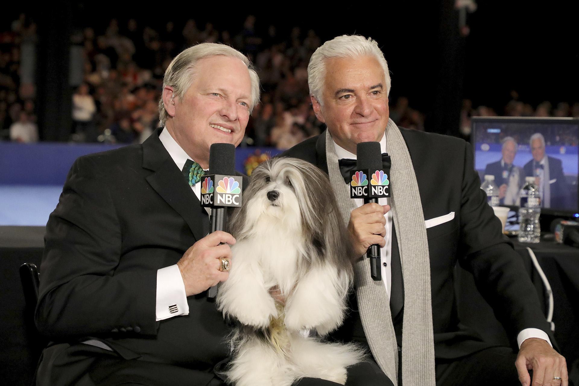 This image released by NBC shows David Frei, left, and host John O'Hurley posing with a havanese dog at The National Dog Show in Philadelphia. The annual parade of pooches has become one of the highest-rated shows of Thanksgiving. (Bill McCay / NBC via AP)