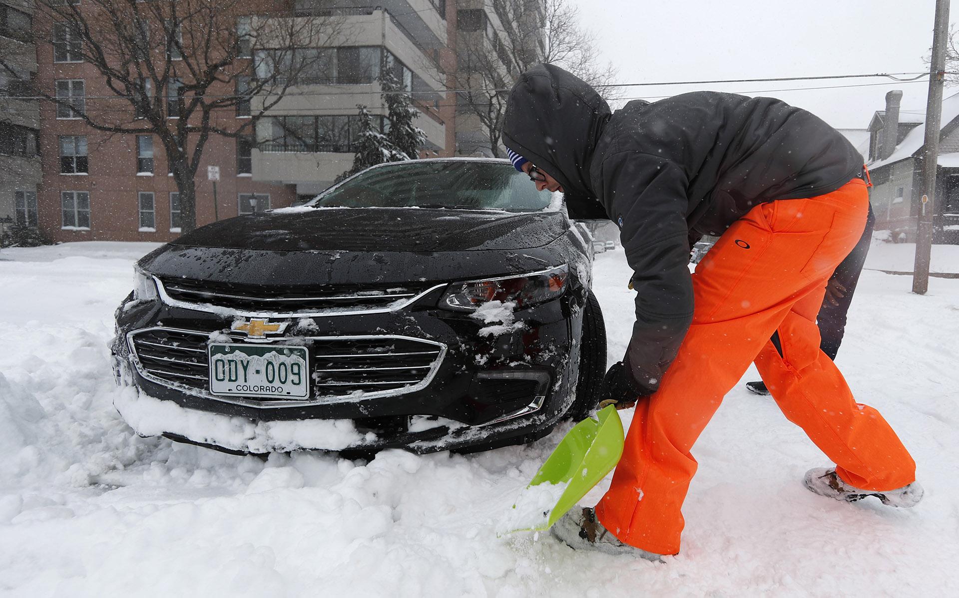 Erik Randa helps dig out a stuck Chevrolet Malibu being used by a ride-sharing service driver out of an intersection at 2nd Ave. and Pearl St. as a storm packing snow and high winds sweeps in over the region Tuesday, Nov. 26, 2019, in Denver. (AP Photo / David Zalubowski)