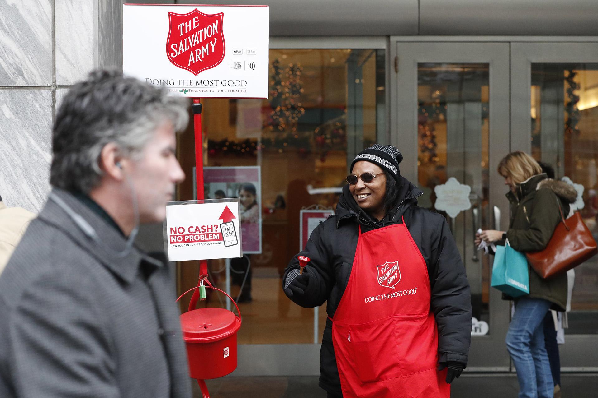 In this Friday, Nov. 15, 2019, photo, bell ringer Carolyn Harper encourages people to donate to the Salvation Army’s annual holiday red kettle campaign on Chicago's Magnificent Mile. (AP Photo / Charles Rex Arbogast)