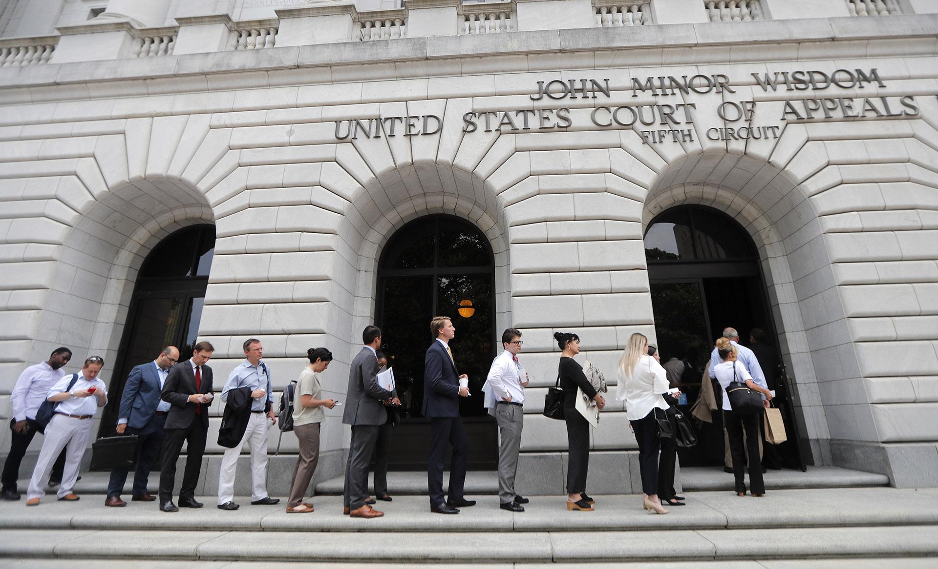 In this Tuesday, July 9, 2019 file photo, people wait in line to enter the 5th Circuit Court of Appeals to sit in overflow rooms to hear arguments in New Orleans. (AP Photo / Gerald Herbert, File)