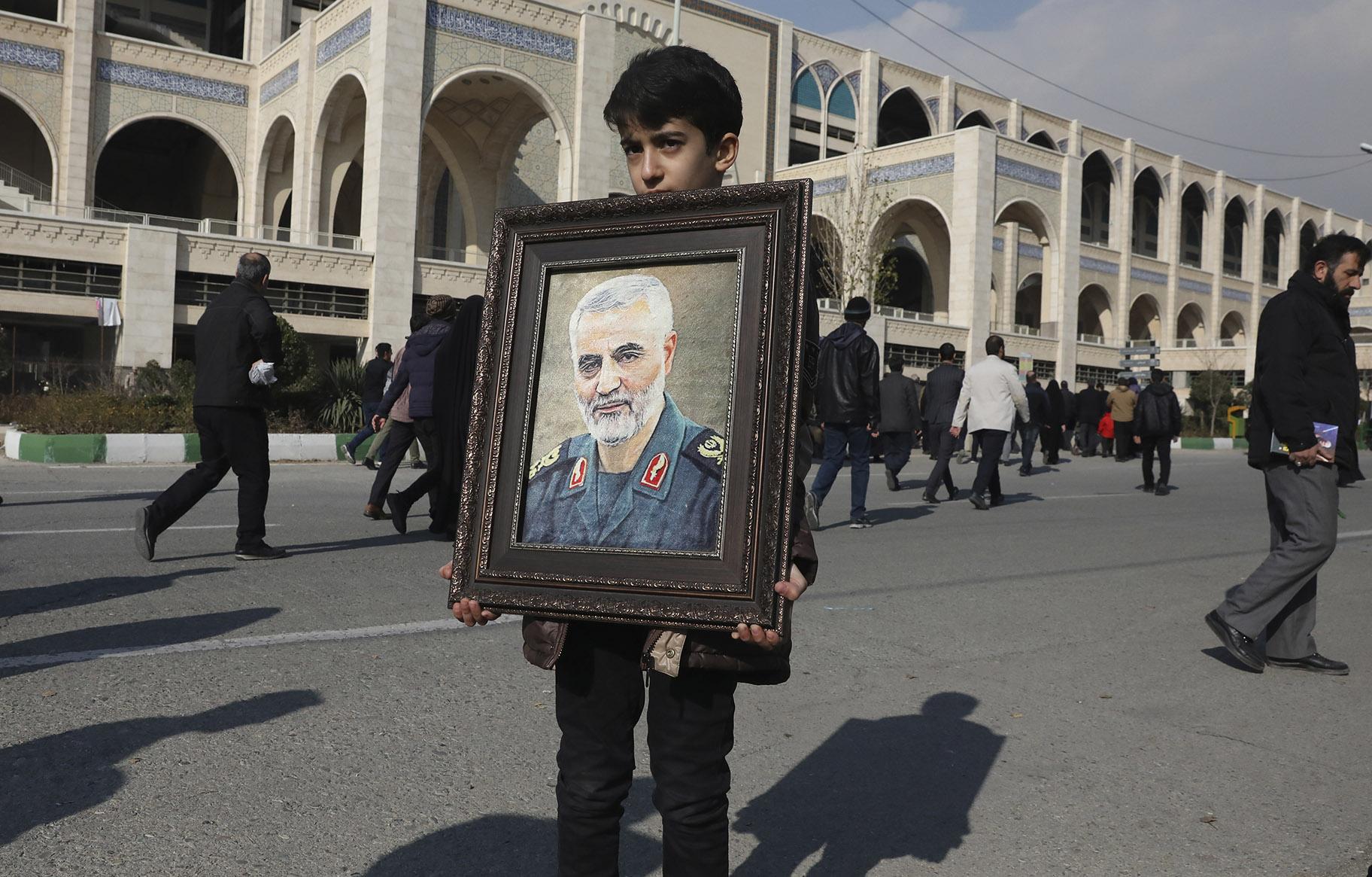 A boy carries a portrait of Iranian Revolutionary Guard Gen. Qassem Soleimani, who was killed in the U.S. airstrike in Iraq, prior to the Friday prayers in Tehran, Iran, Friday Jan. 3, 2020. (AP Photo / Vahid Salemi)