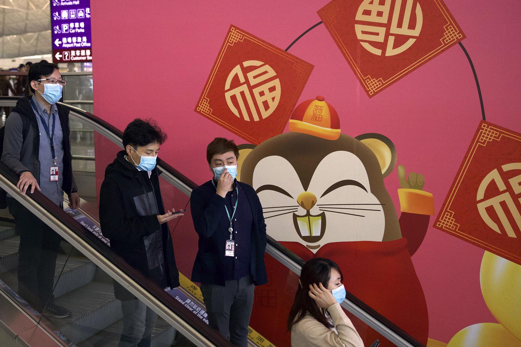 People wear face masks as they ride an escalator at the Hong Kong International Airport in Hong Kong, Tuesday, Jan. 21, 2020. (AP Photo / Ng Han Guan)