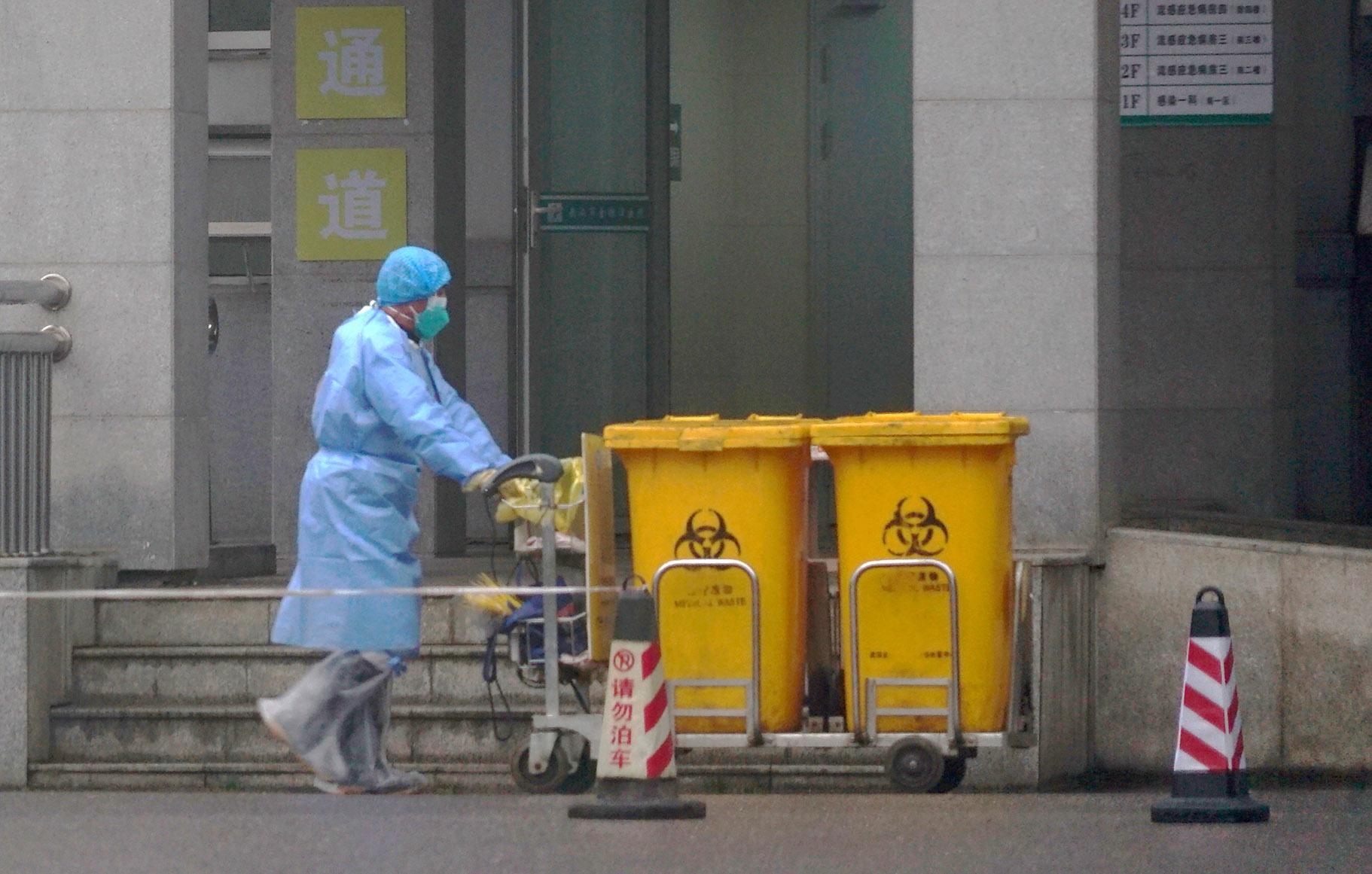 In this Wednesday, Jan. 22, 2020, file photo, a staff member moves bio-waste containers past the entrance of the Wuhan Medical Treatment Center in Wuhan, China, where some people infected with a new virus are being treated. (AP Photo / Dake Kang, File)