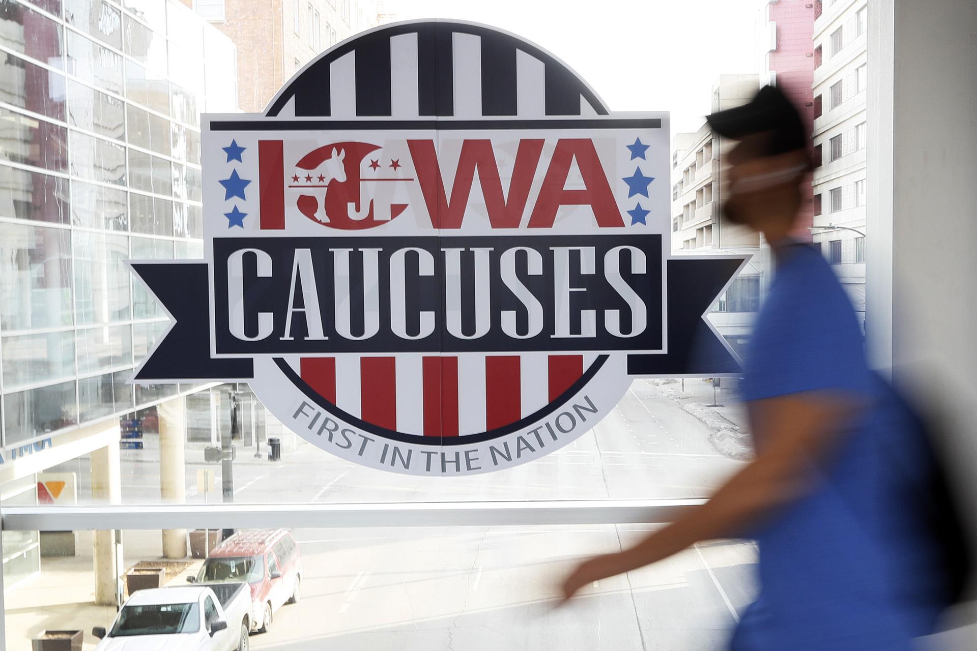 A pedestrian walks past a sign for the Iowa Caucuses on a downtown skywalk, Tuesday, Feb. 4, 2020, in Des Moines, Iowa. (AP Photo / Charlie Neibergall)