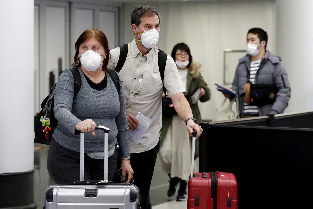 Travelers wear protective mask as they walk through in terminal 5 at O’Hare International Airport in Chicago, Sunday, March 1, 2020. (AP Photo / Nam Y. Huh)