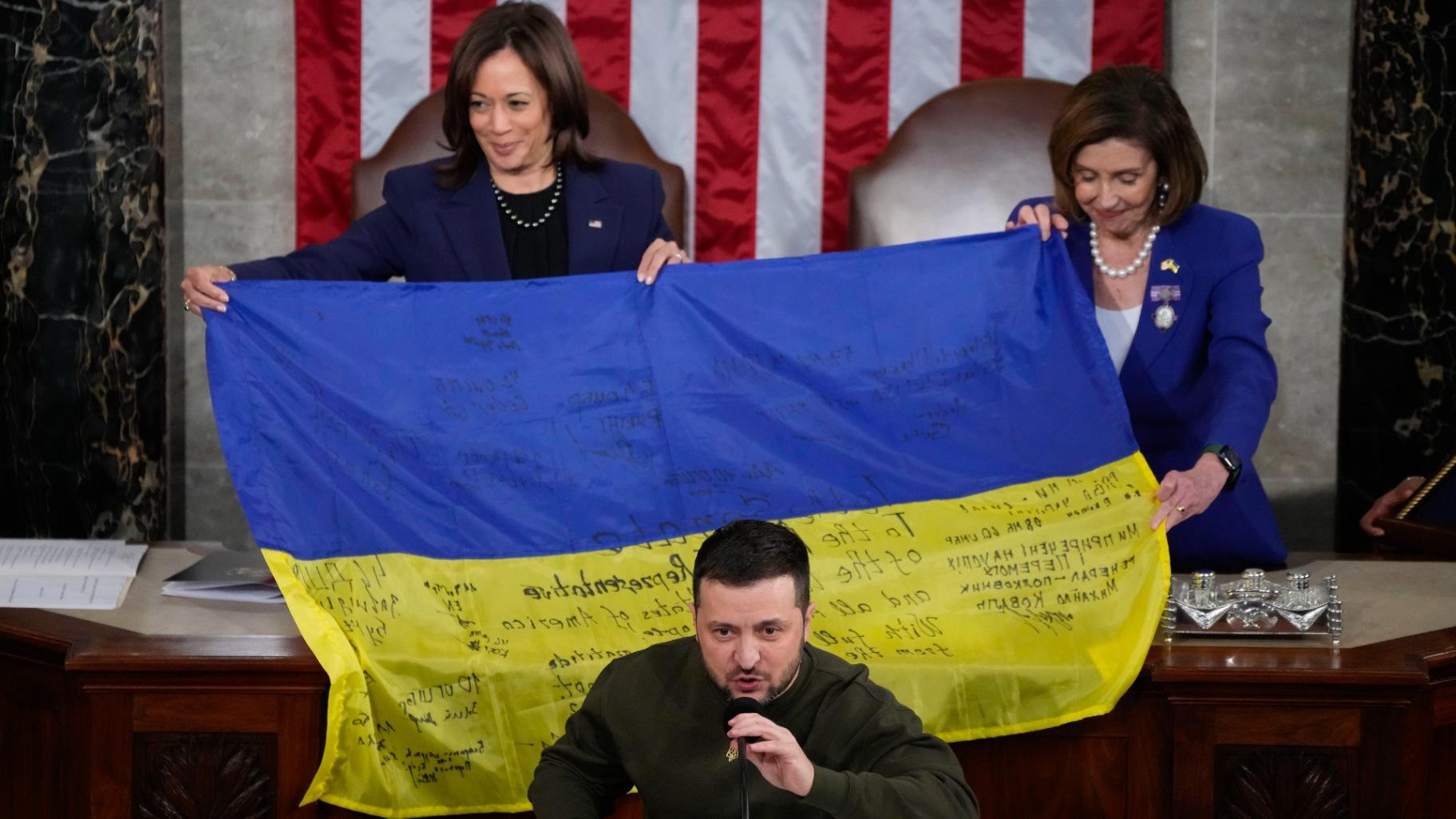 Vice President Kamala Harris and House Speaker Nancy Pelosi of Calif., right, react as Ukrainian President Volodymyr Zelenskyy presents lawmakers with a Ukrainian flag autographed by front-line troops in Bakhmut, in Ukraine's contested Donetsk province, as he addresses a joint meeting of Congress on Capitol Hill in Washington, Wednesday, Dec. 21, 2022. (AP Photo / Jacquelyn Martin)