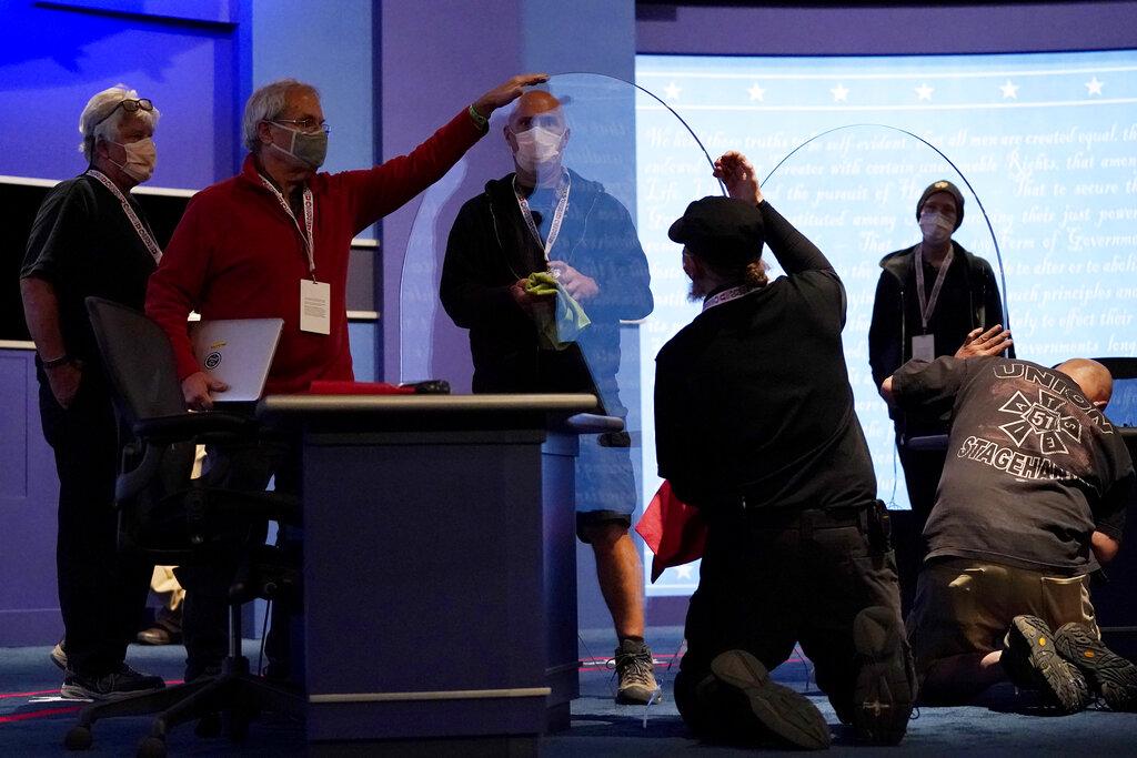 Members of the production crew inspect glass on stage which will serve as a barrier to protect the spread of COVID-19 as preparations take place for the vice presidential debate at the University of Utah, Tuesday, Oct. 6, 2020, in Salt Lake City. (AP Photo / Julio Cortez)