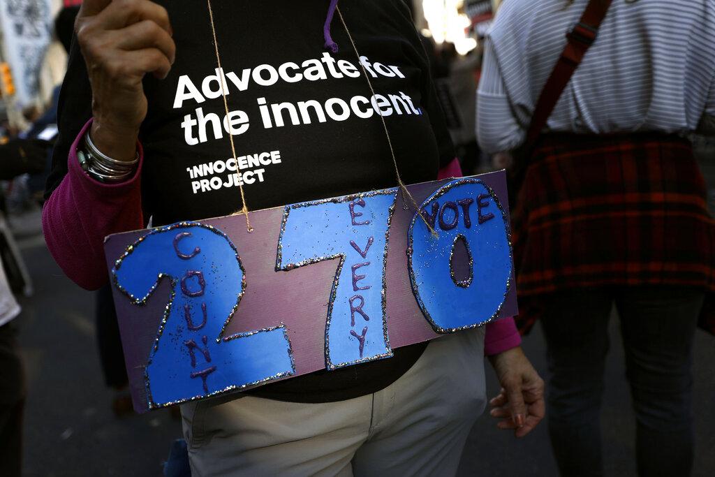A person holds a sign referring to the number of electoral votes needed to win the presidency while demonstrating outside the Pennsylvania Convention Center where votes are being counted, Thursday, Nov. 5, 2020, in Philadelphia, following Tuesday’s election. (AP Photo / Rebecca Blackwell)