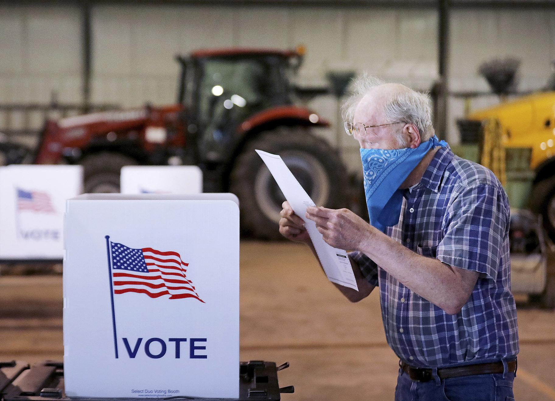 Robert Wilson reviews his selections on his ballot while voting at the town’s highway garage building Tuesday, April 7, 2020 in Dunn, Wis. (John Hart / Wisconsin State Journal via AP)