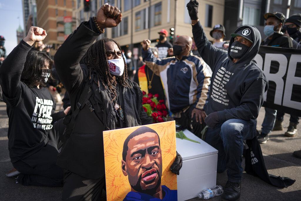 Cortez Rice, left, of Minneapolis, sits with others in the middle of Hennepin Avenue on Sunday, March 7, 2021, in Minneapolis, Minn., to mourn the death of George Floyd a day before jury selection is set to begin in the trial of former Minneapolis officer Derek Chauvin, who is accused of killing Floyd. (Jerry Holt / Star Tribune via AP)