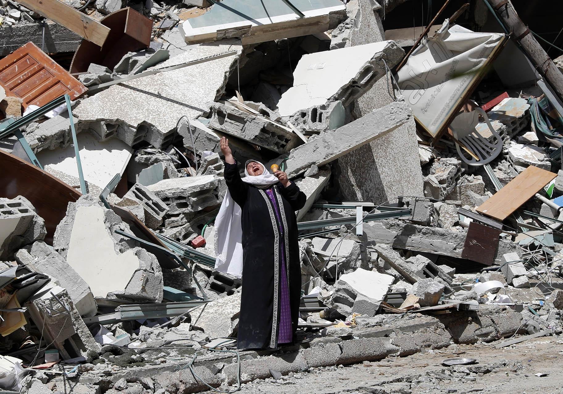 A woman reacts while standing near the rubble of a building that was destroyed by an Israeli airstrike on Saturday that housed The Associated Press, broadcaster Al-Jazeera and other media outlets, in Gaza City, Sunday, May 16, 2021. (AP Photo / Adel Hana)