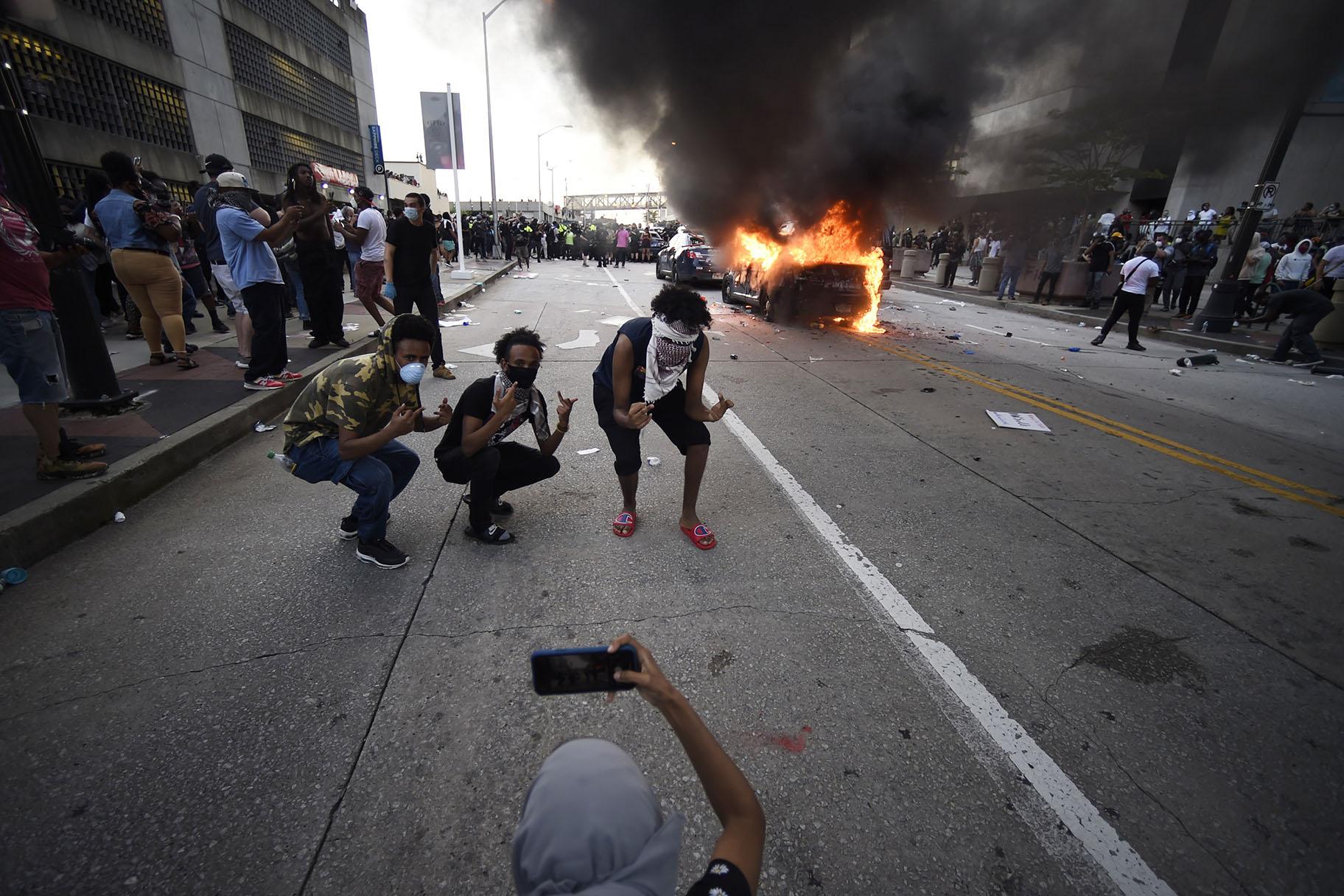 An Atlanta Police Department vehicle burns as people pose for a photo during a demonstration against police violence, Friday, May 29, 2020, in Atlanta. (AP Photo / Mike Stewart)