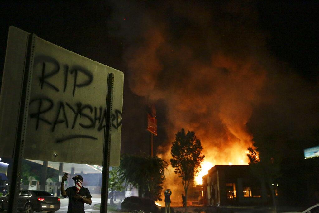 “RIP Rayshard” is spray painted on a sign as flames engulf a Wendy’s restaurant during protests Saturday, June 13, 2020, in Atlanta. (AP Photo / Brynn Anderson)