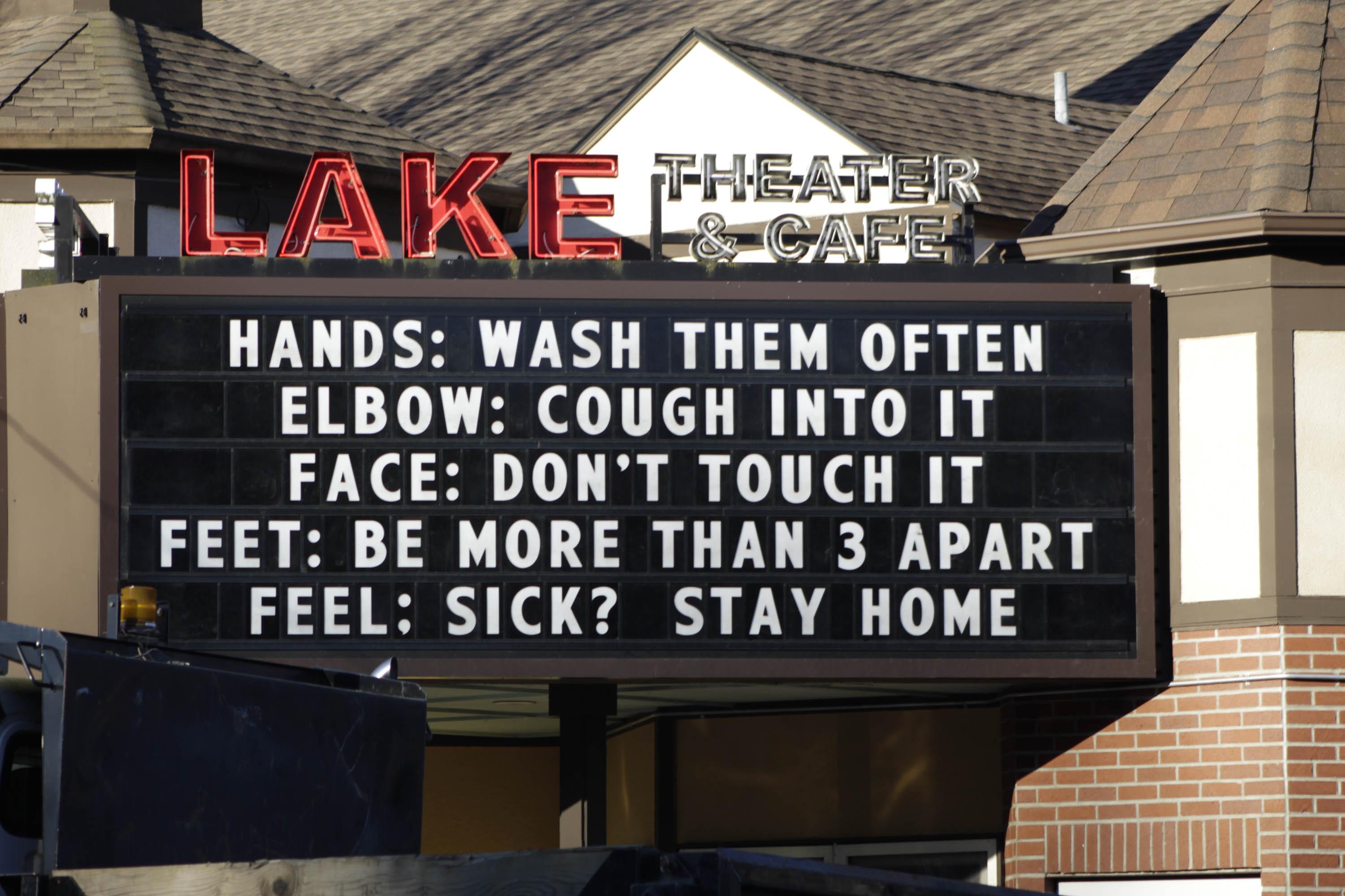 In this March 17, 2020 file photo, a marquee outside the Lake Theater & Café in downtown Lake Oswego, Oregon, reminds people to practice social distancing and stay home if sick. (AP Photo / Gillian Flaccus, File)