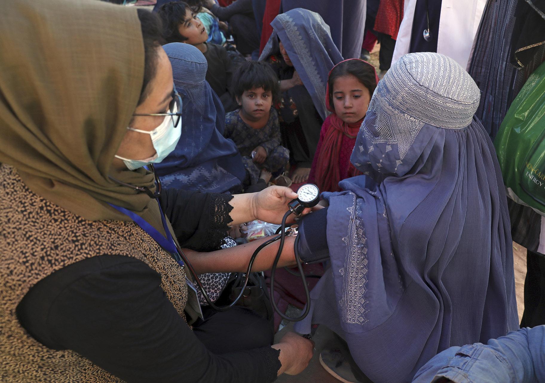 In this Aug. 10, 2021 file photo, an internally displaced woman from northern provinces, who fled her home due to fighting between the Taliban and Afghan security personnel, has her blood pressure taken after taking refuge in a public park in Kabul, Afghanistan. (AP Photo / Rahmat Gul, File)