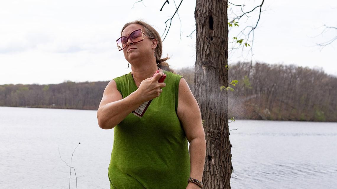 Amanda Allen Hall sprays herself with tick repellent April 4, 2026, at Lake Murphysboro State Park. Hall takes extra precaution after a tick bite led to alpha-gal. (Riley Sembler)  