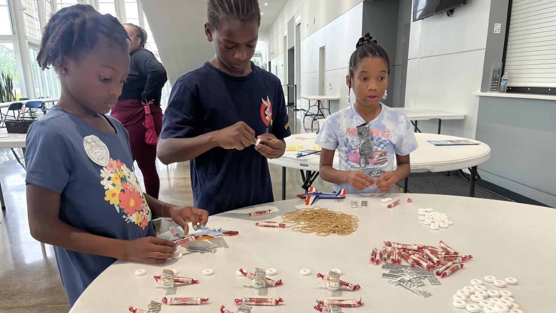 Students prepare homemade planes out of rubber bands and candy at the Community Aviation Expo on June 28, 2024. (Angel Idowu / WTTW News)