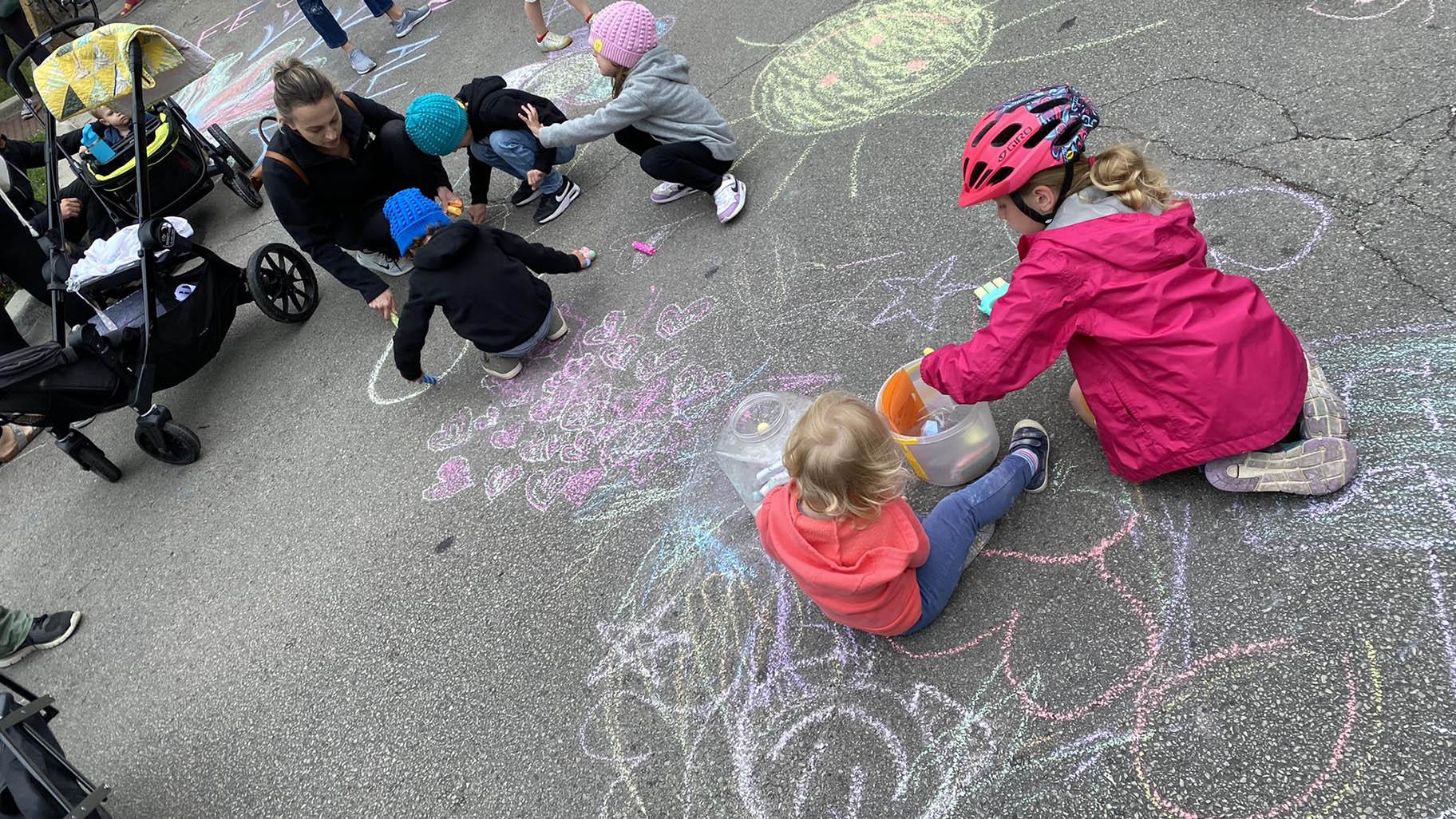 Children draw chalk art in the street on June 12, 2022, at the Lincoln Square intersection where 2-year-old Rafi Cardenas was killed by a driver while crossing the street. (Nick Blumberg / WTTW News)