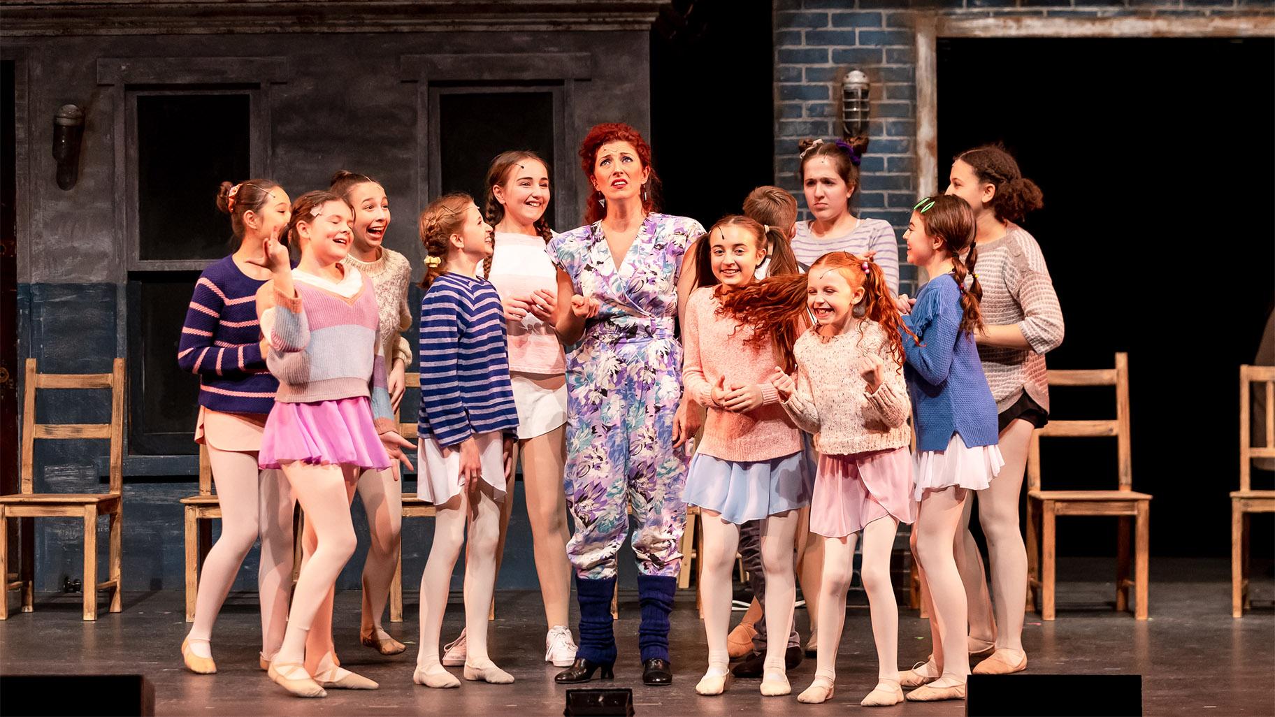 It is the bitter but insightful Mrs. Wilkerson (Casiena Raether) — a neighborhood dance teacher who never made it as a dancer herself — who notices Billy’s innate gift the moment he joins her class. The class full of giggly young girls, includes her sassy little daughter, Debbie (Everleigh Murphy, who easily lights up the stage). (Credit: Brett Beiner)