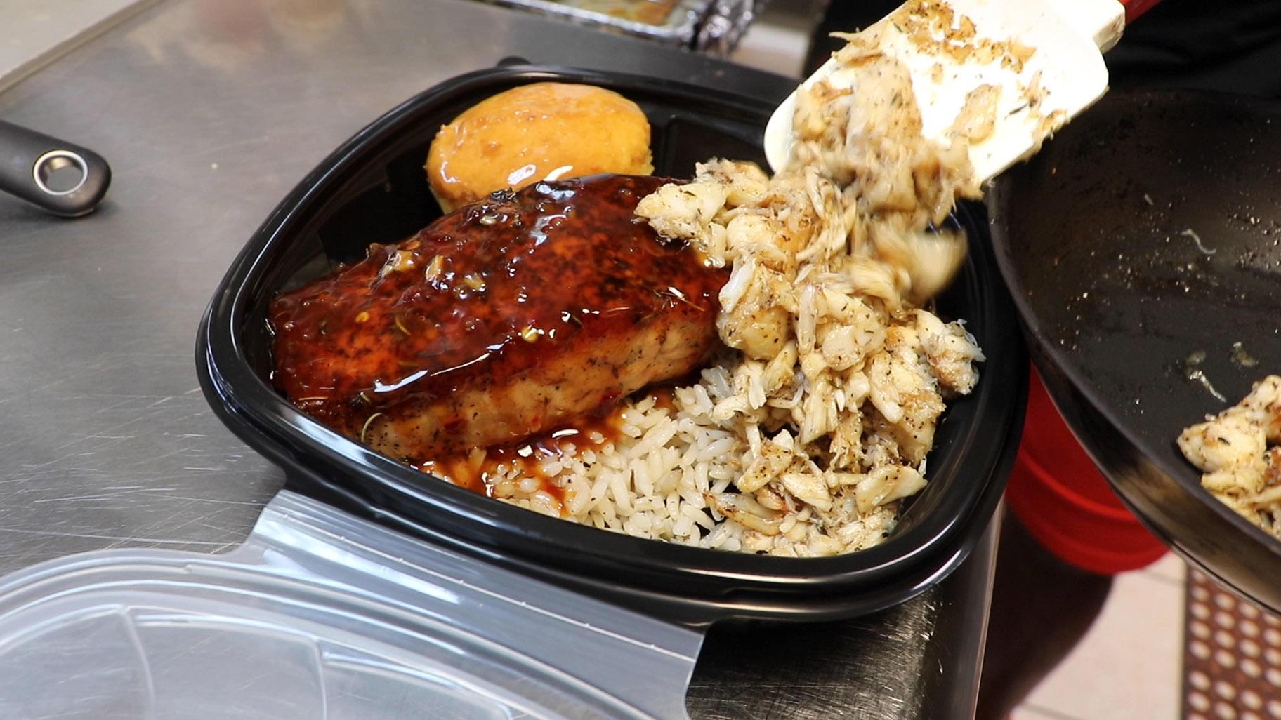 Creole-buttered lump crab meat and pan-seared salmon with sweet chili sauce is placed in a to-go box at Cleo’s Southern Cuisine in Chicago’s Bronzeville neighborhood on June 27, 2020. (Evan Garcia / WTTW News)