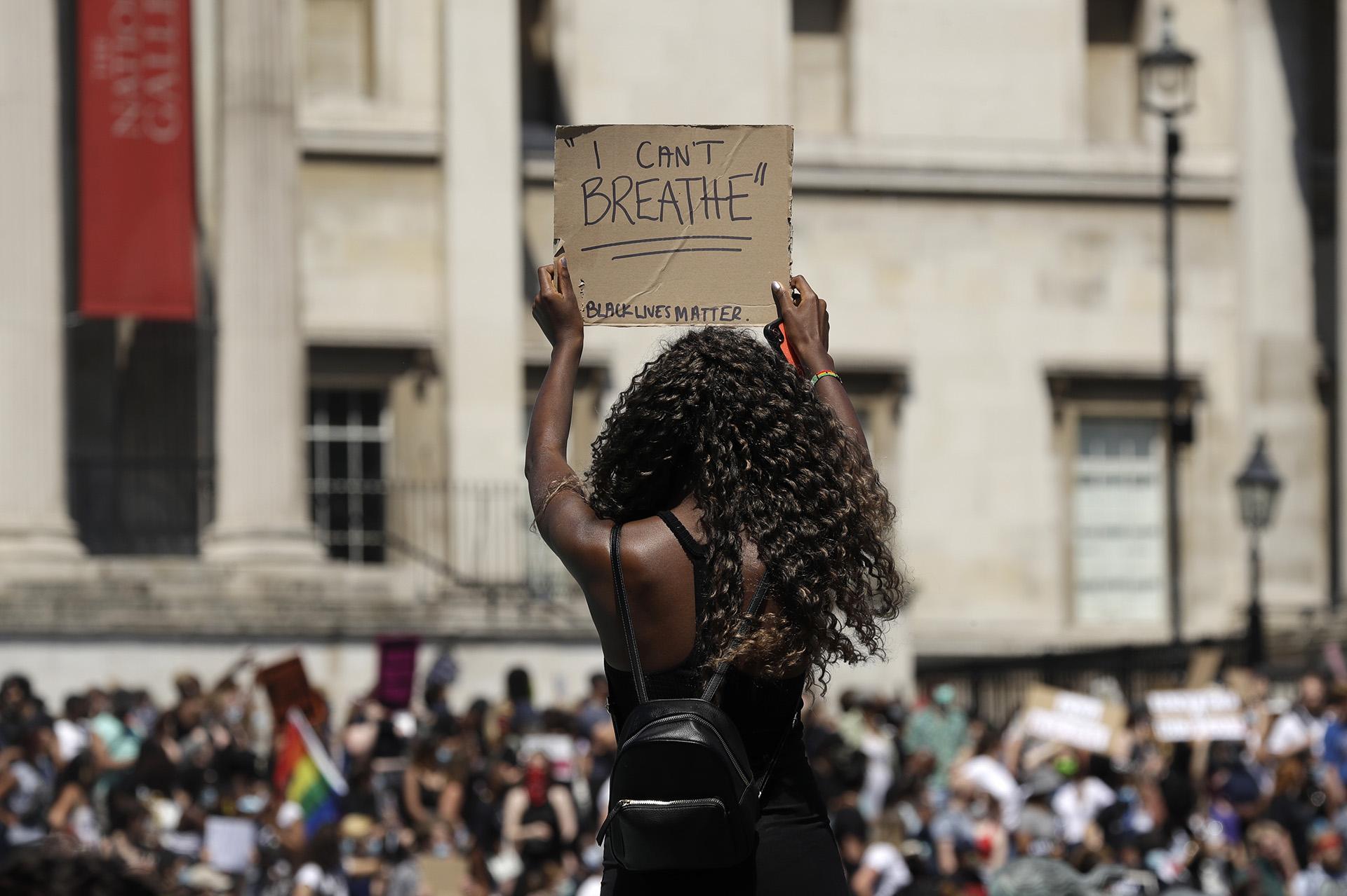 A woman holds up a banner as people gather in Trafalgar Square in central London on Sunday, May 31, 2020 to protest against the recent killing of George Floyd by police officers in Minneapolis that has led to protests across the U.S. (AP Photo / Matt Dunham)