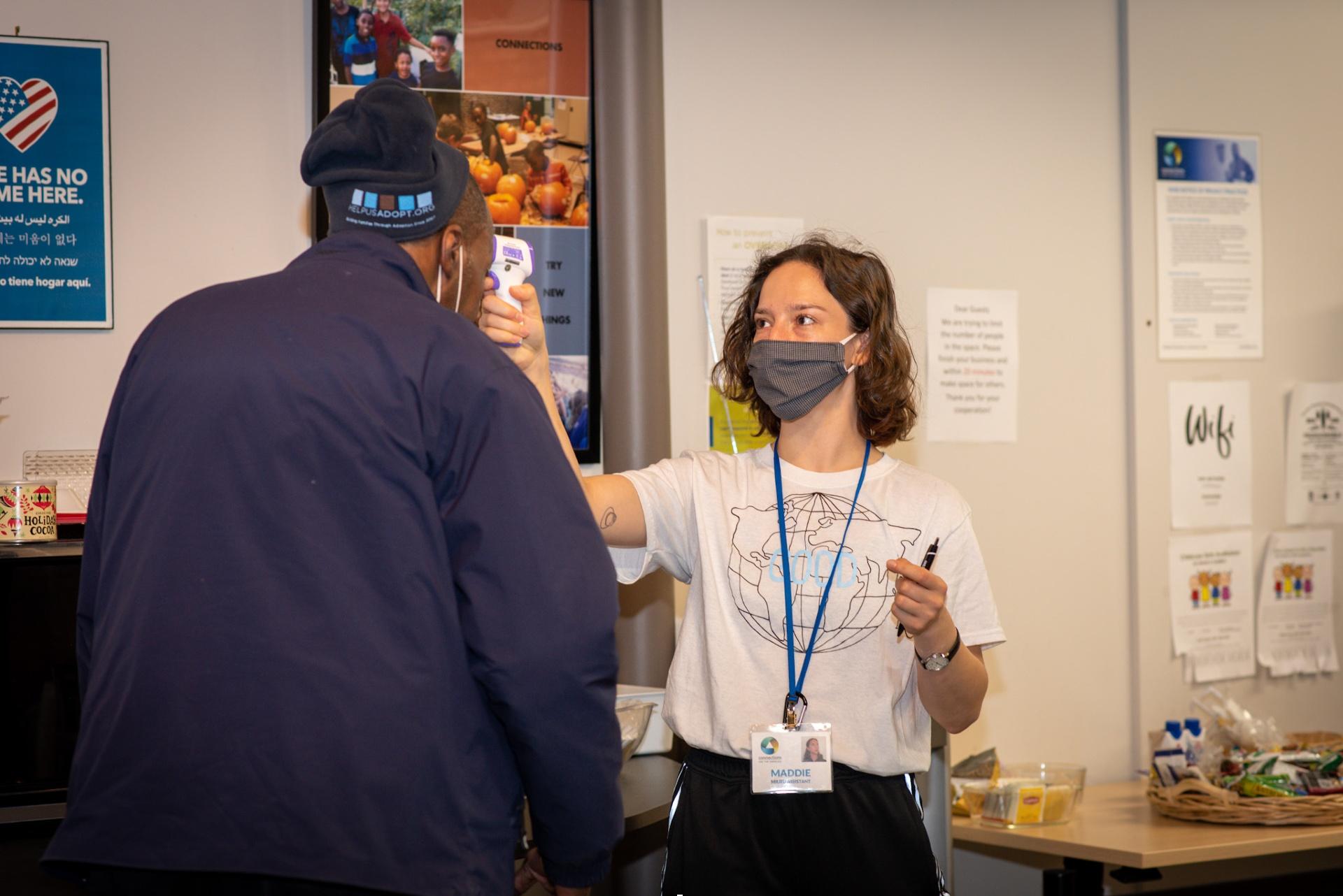 A staff member at Connections for the Homeless takes a person’s temperature. (Credit: Hex Hernandez Photography)