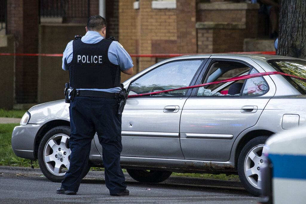 A Chicago police officer investigates the scene of a shooting in Chicago on Sunday, July 5, 2020. (Ashlee Rezin Garcia / Chicago Sun-Times via AP)