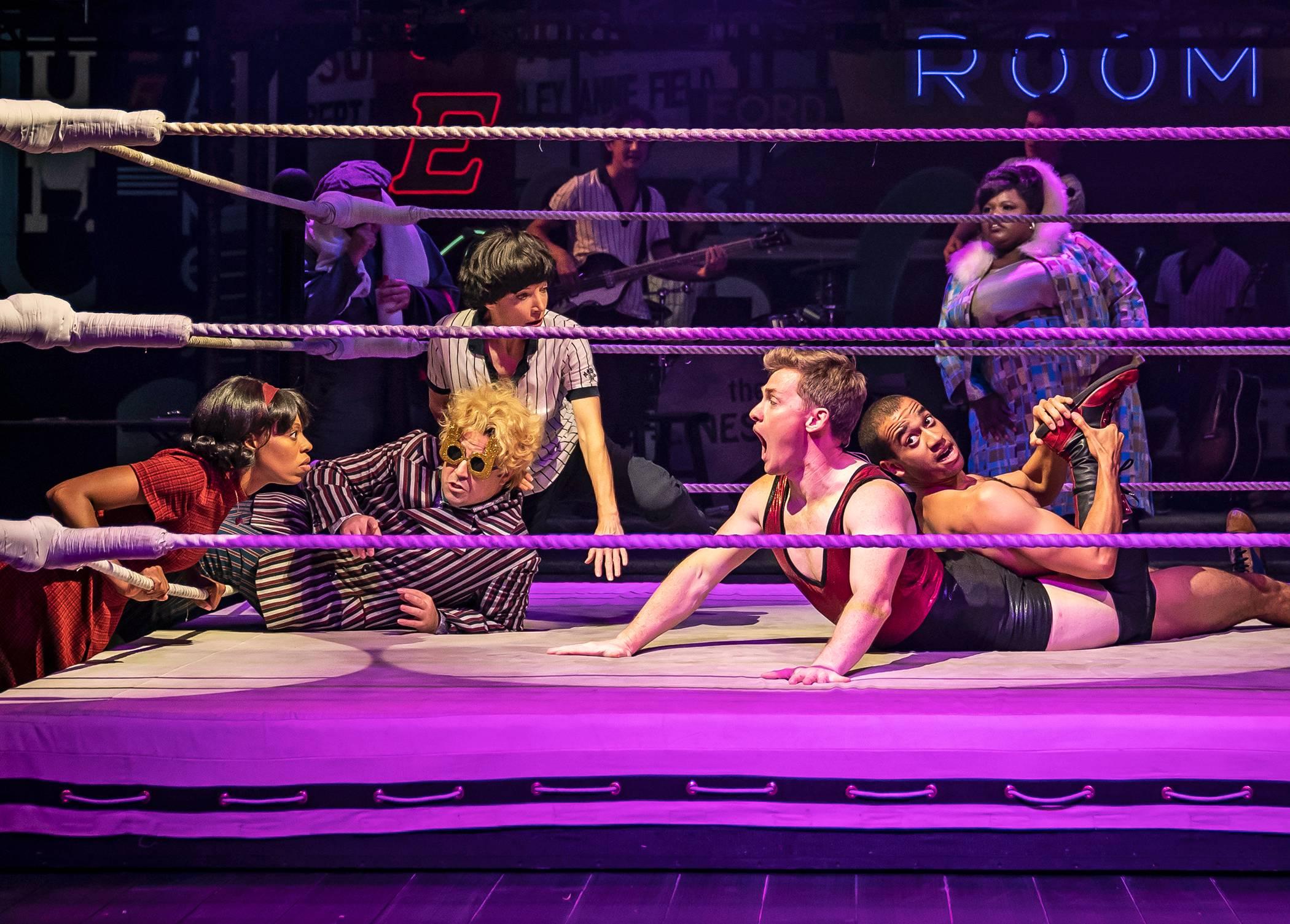 Orlando (Liam Quealy) and Rosalind (Lakeisha Renee) lock eyes from across the ring, observed by Touchstone (Kayvon Khoshkam), LeBeau (Deborah Hay), and Charles (Austin Eckert) in Chicago Shakespeare Theater’s production of “As You Like It,” adapted and directed by Daryl Cloran, in the Courtyard Theater, Oct. 6–Nov. 21. (Photo by Liz Lauren)