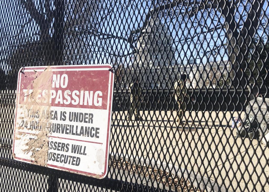 Members of the National Guard stand inside anti-scaling fencing that surrounds the Capitol complex, Sunday, Jan. 10, 2021, in Washington. (AP Photo / Alan Fram)