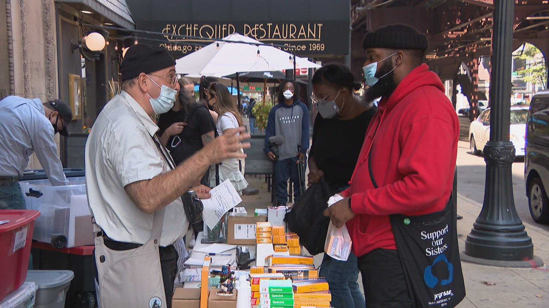 Central Camera owner Don Flesch, left, speaks with a customer at his store’s temporary outdoor operation on Oct. 9, 2020. (WTTW News)