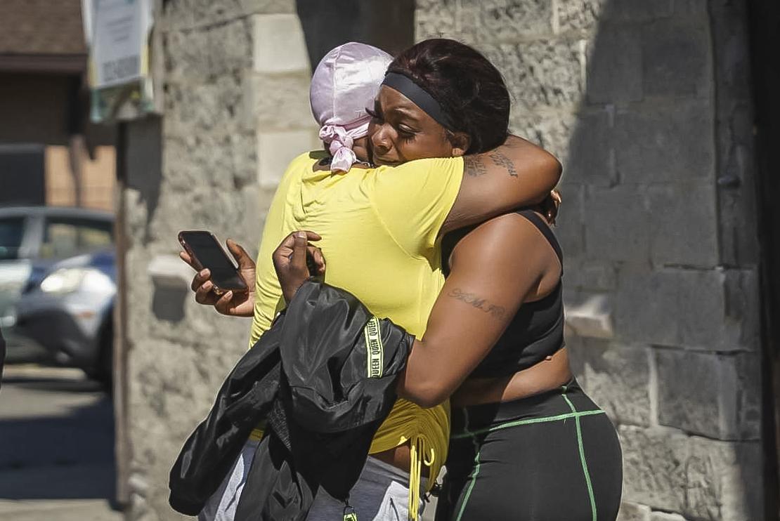 A woman receives a hug from a supporter outside the scene of a shooting outside a home in Chicago, Tuesday, June 15, 2021. (Ashlee Rezin Garcia / Chicago Sun-Times via AP)
