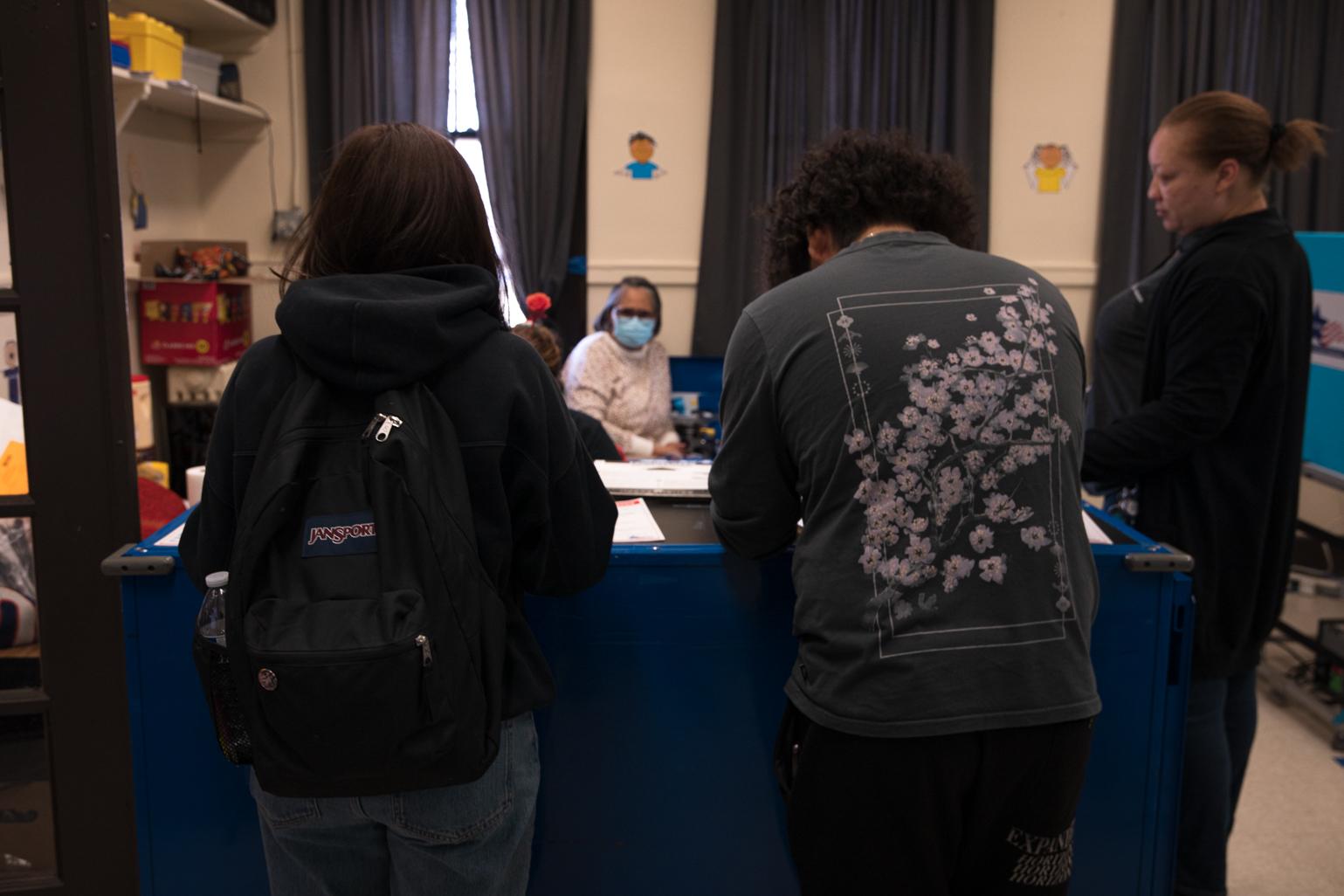 Two seniors from Kelvyn Park High School register to vote at the Kilbourn Park polling station on Feb. 21, 2023. (Michael Izquierdo / WTTW News)