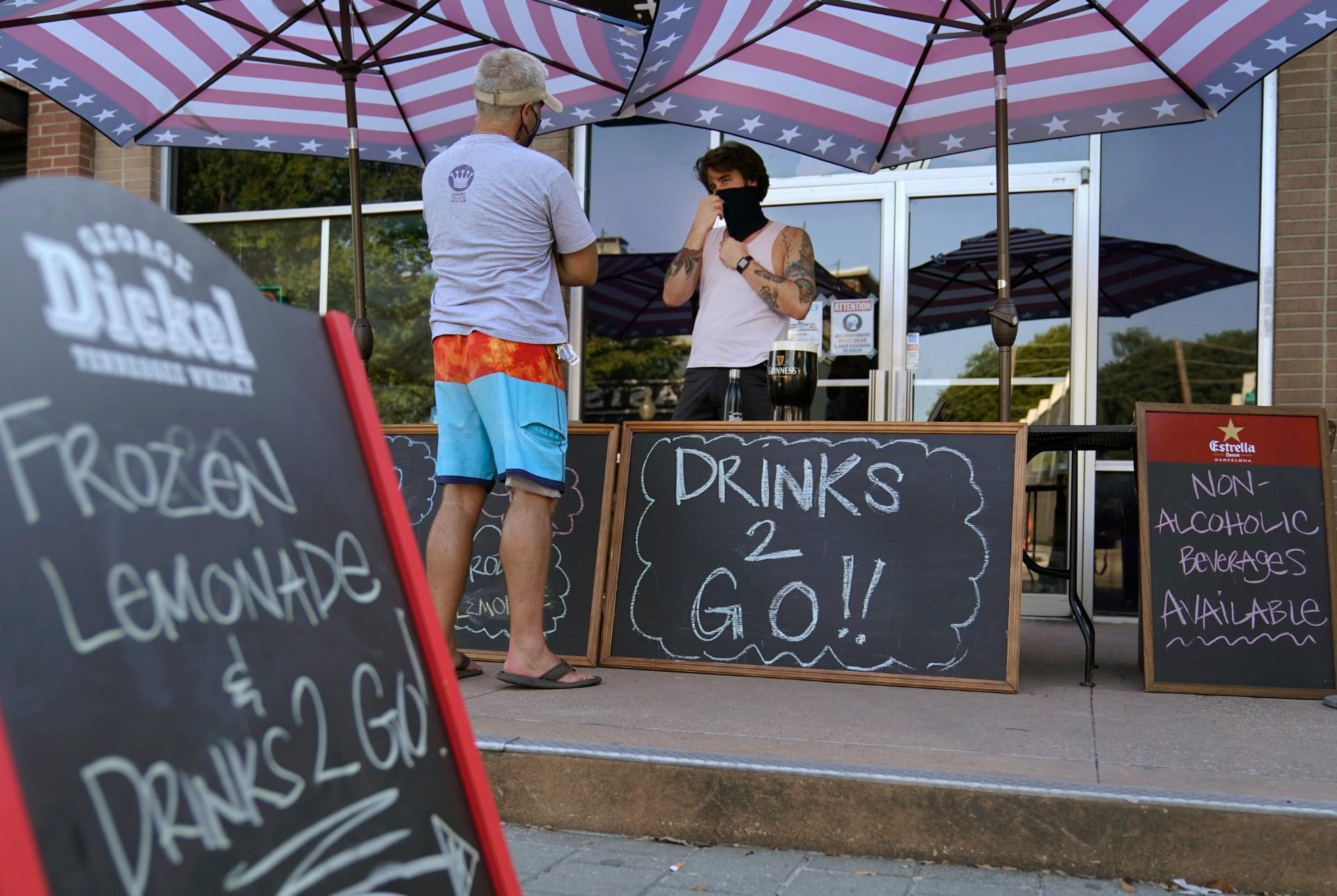 A drinks-to-go table is set up outside the Old Crow bar on Greenville Avenue in Dallas, Thursday, Aug. 13, 2020. Some states and cities in the U.S. are allowing cocktails to go due to the pandemic. (AP Photo / LM Otero)