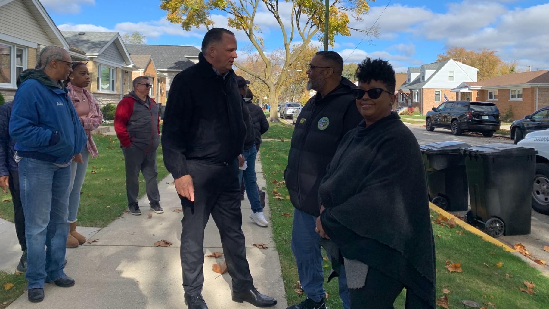 Foreground from left to right, Department of Streets and Sanitation Commissioner Cole Stallard, Ald. Christopher Taliaferro (29th Ward) and Chicago first lady Stacie Johnson on Nov. 12, 2024, in the Dunning neighborhood after greeting residents who received a free backyard compost bin. (Eunice Alpasan / WTTW News)