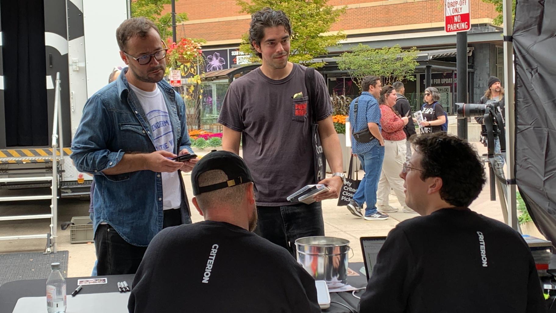 Sam Velazquez, 32, of Roscoe Village, left, and his friend Andrew Conroy, right, were the first people in line for the Criterion Mobile Closet stop in Chicago on Oct. 17, 2025. (Eunice Alpasan / WTTW News)
