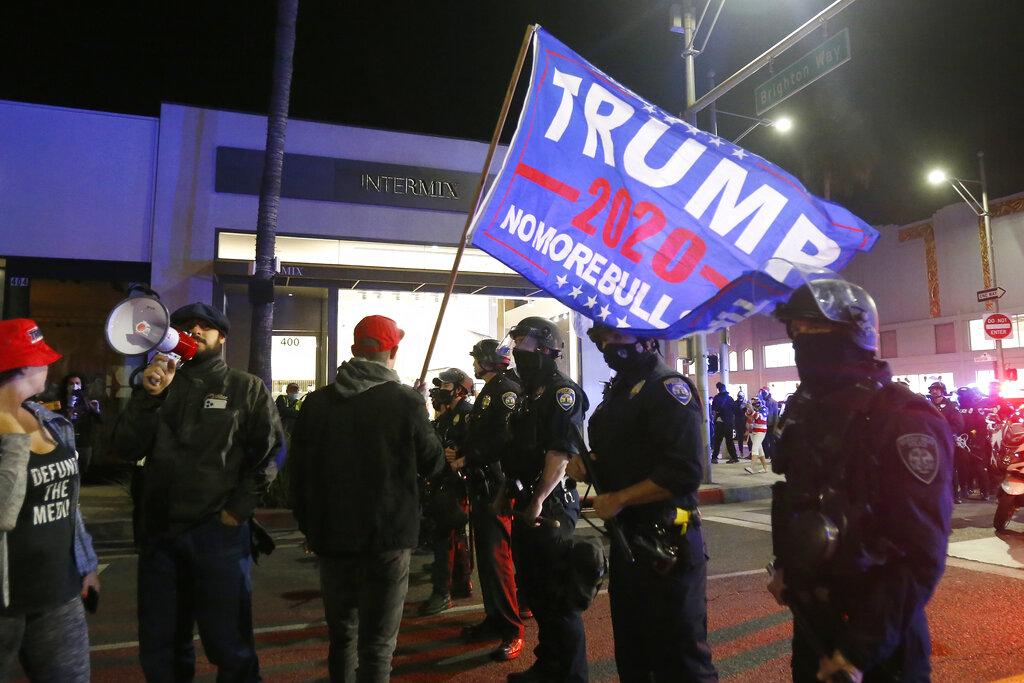 Police officers stand in front of supporters of President Donald Trump marching in Beverly Hills, Calif., Saturday, Nov. 7, 2020. (AP Photo / Ringo H.W. Chiu)