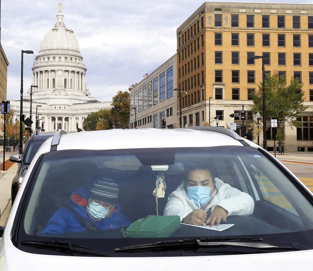 In this Oct. 20, 2020, photo, Evelio Mancera and his daughter, Jennifer Mancera, both residents of Madison, fill out their ballots on the first day of the state’s in-person absentee voting window for the Nov. 3 election outside the city’s City-County Building Tuesday in Madison, Wis. (John Hart / Wisconsin State Journal via AP)