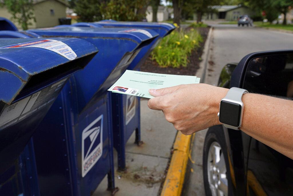 In this Tuesday, Aug. 18, 2020, file photo, a person drops applications for mail-in-ballots into a mail box in Omaha, Neb. (AP Photo / Nati Harnik, File)