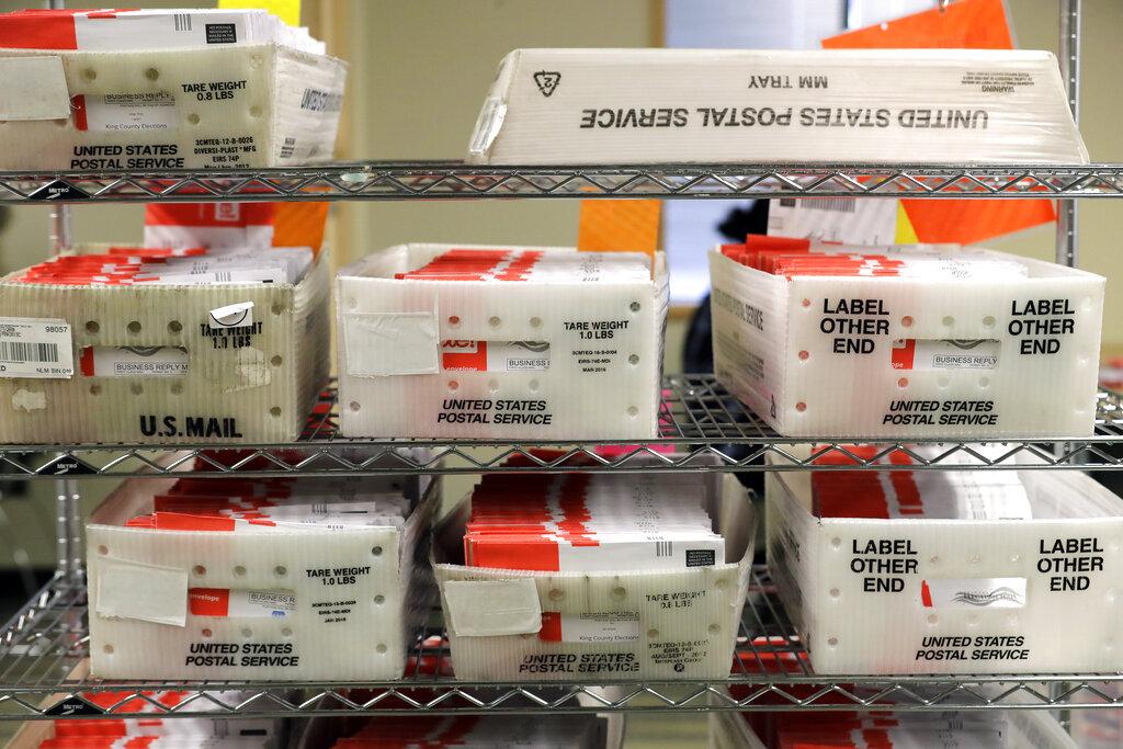 In this Aug. 5, 2020, file photo vote-by-mail ballots are shown in U.S. Postal service sorting trays the King County Elections headquarters in Renton, Wash., south of Seattle. (AP Photo / Ted S. Warren, File)