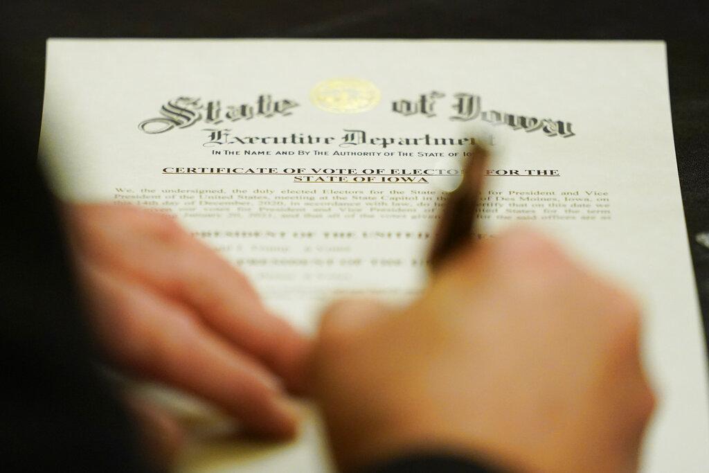 A member of Iowa’s Electoral College signs the Certificate of Vote of Electors for the State of Iowa, Monday, Dec. 14, 2020, at the Statehouse in Des Moines, Iowa. (AP Photo / Charlie Neibergall)