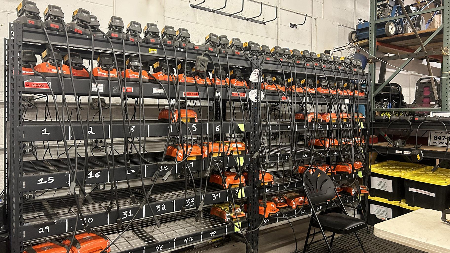 Racks of electric leaf blower chargers are pictured at Nature’s Perspective Landscaping in Evanston. (Blair Paddock / WTTW News)