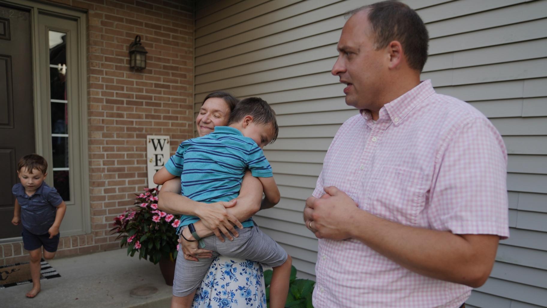 Lizzy Taggart holds her son Fulton, 8, while standing with her husband, Joe, outside their home in Bloomington, Ill., on July 16, 2026. (AP Photo / Jessie Wardarski)