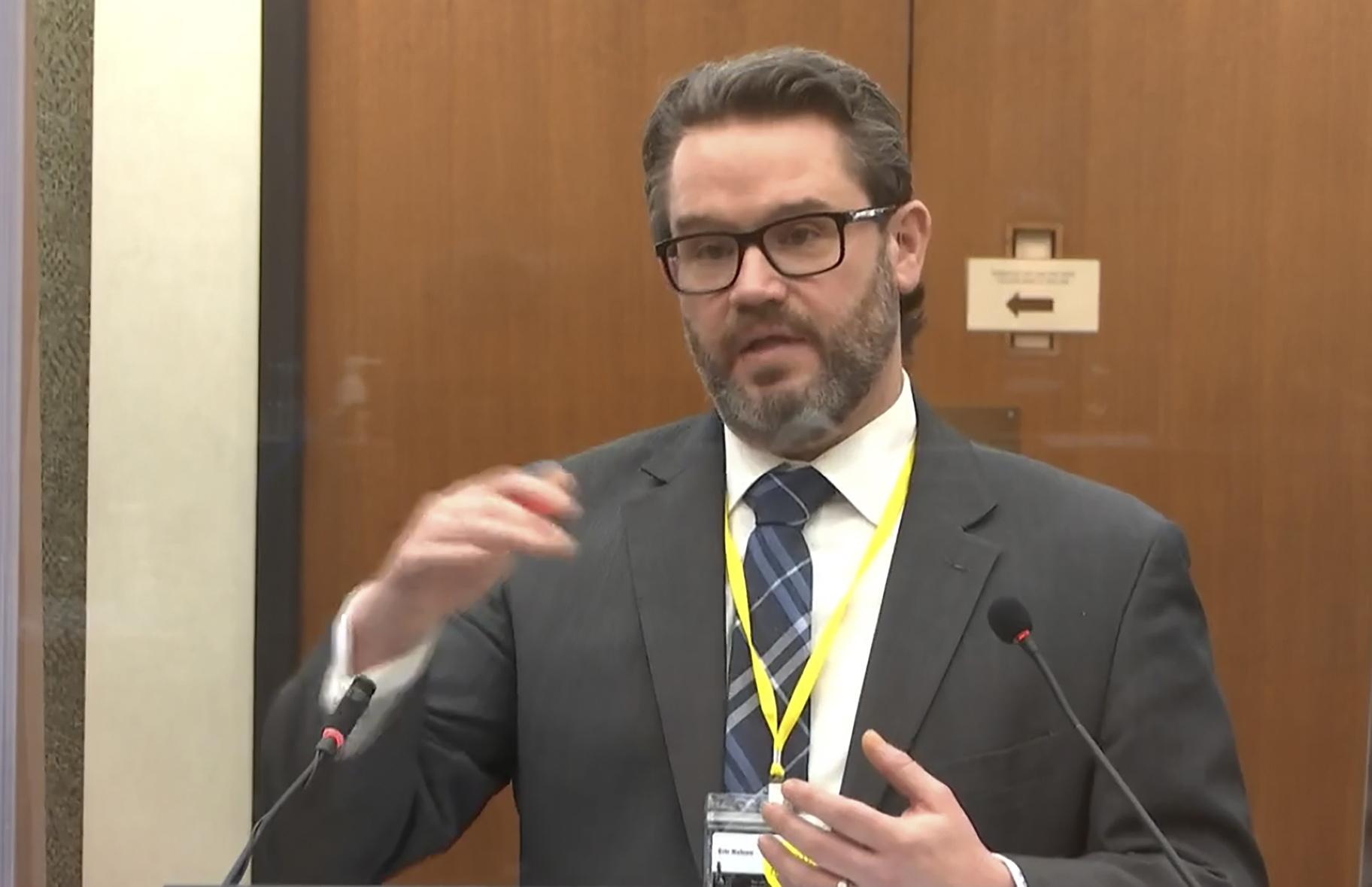 In this image from video, defense attorney Eric Nelson questions Dr. Andrew Baker, Hennepin County Chief Medical Examiner, as Hennepin County Judge Peter Cahill presides Friday, April 9, 2021, in the trial of former Minneapolis police Officer Derek Chauvin at the Hennepin County Courthouse in Minneapolis, Minn. (Court TV via AP, Pool)