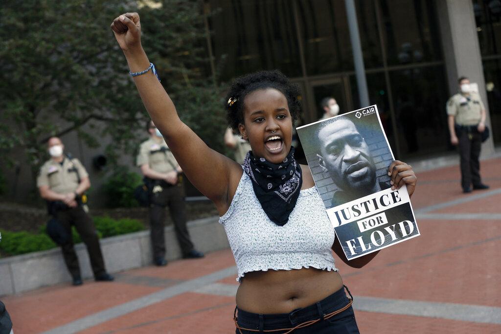 In this Thursday, May 28, 2020, file photo, a protester holds a photo of George Floyd during a protest at the Hennepin County Government Center, as protests continue over the death of Floyd, who died in police custody Monday night in Minneapolis, after video shared online by a bystander showed a white officer kneeling on his neck during his arrest as he pleaded that he couldn’t breathe. (AP Photo / Jim Mone, File)