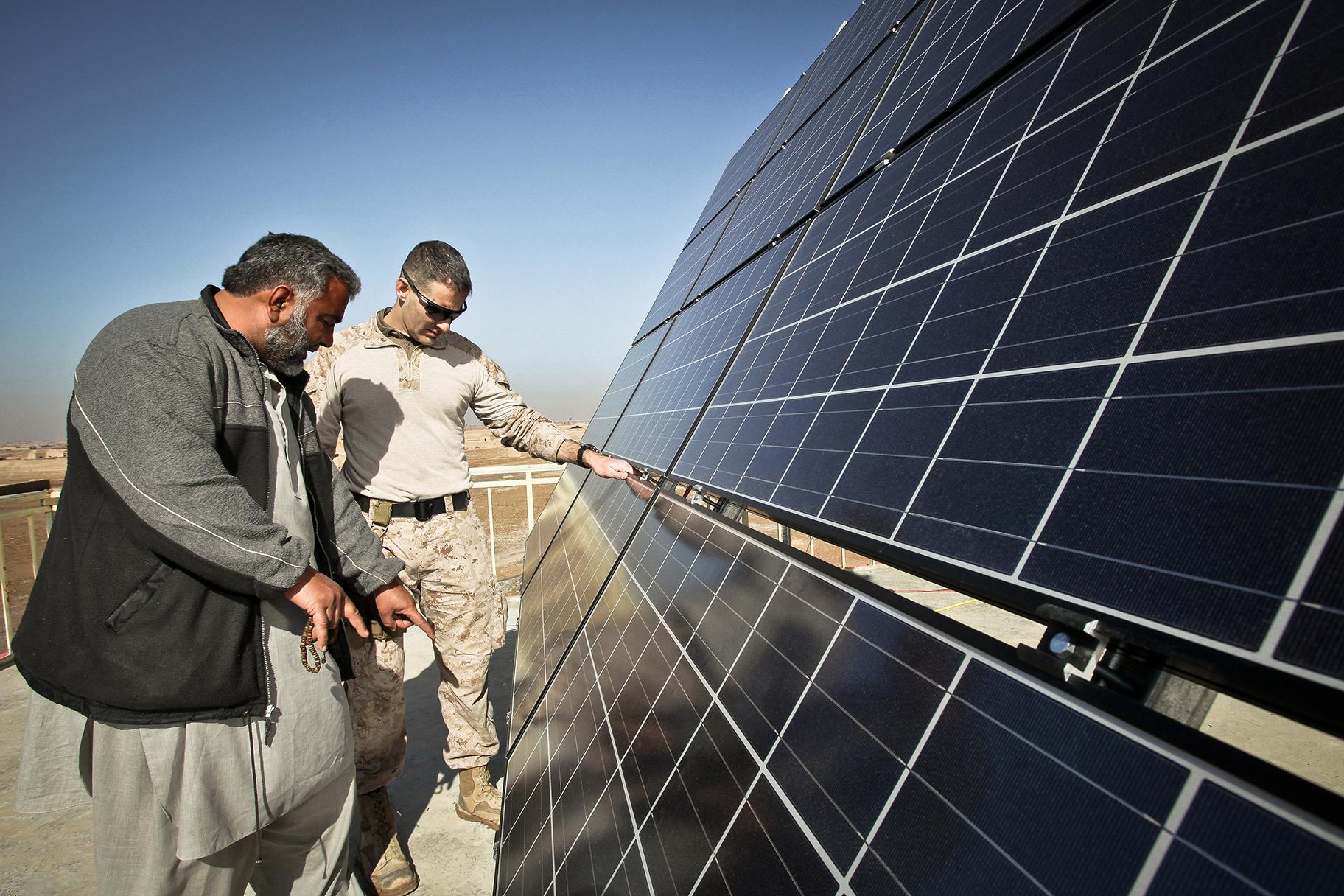 Maj. Erich Bergiel, right, inspects the solar panels on the roof of the Marjeh Fruit and Vegetable Packing Facility in Afghanistan while he talks with Abdul Rahman, a renewable energy engineer. (Master Gunnery Sgt. Phil Mehringer / U.S. Department of Defense) 