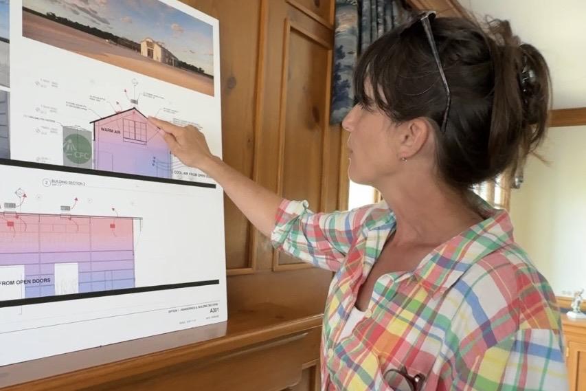 Talking through renderings of a planned seed nursery, Abigail Derby Lewis points out sustainable features including wind turbines, solar attic fans and a 7,000-gallon cistern. (Patty Wetli / WTTW News)  