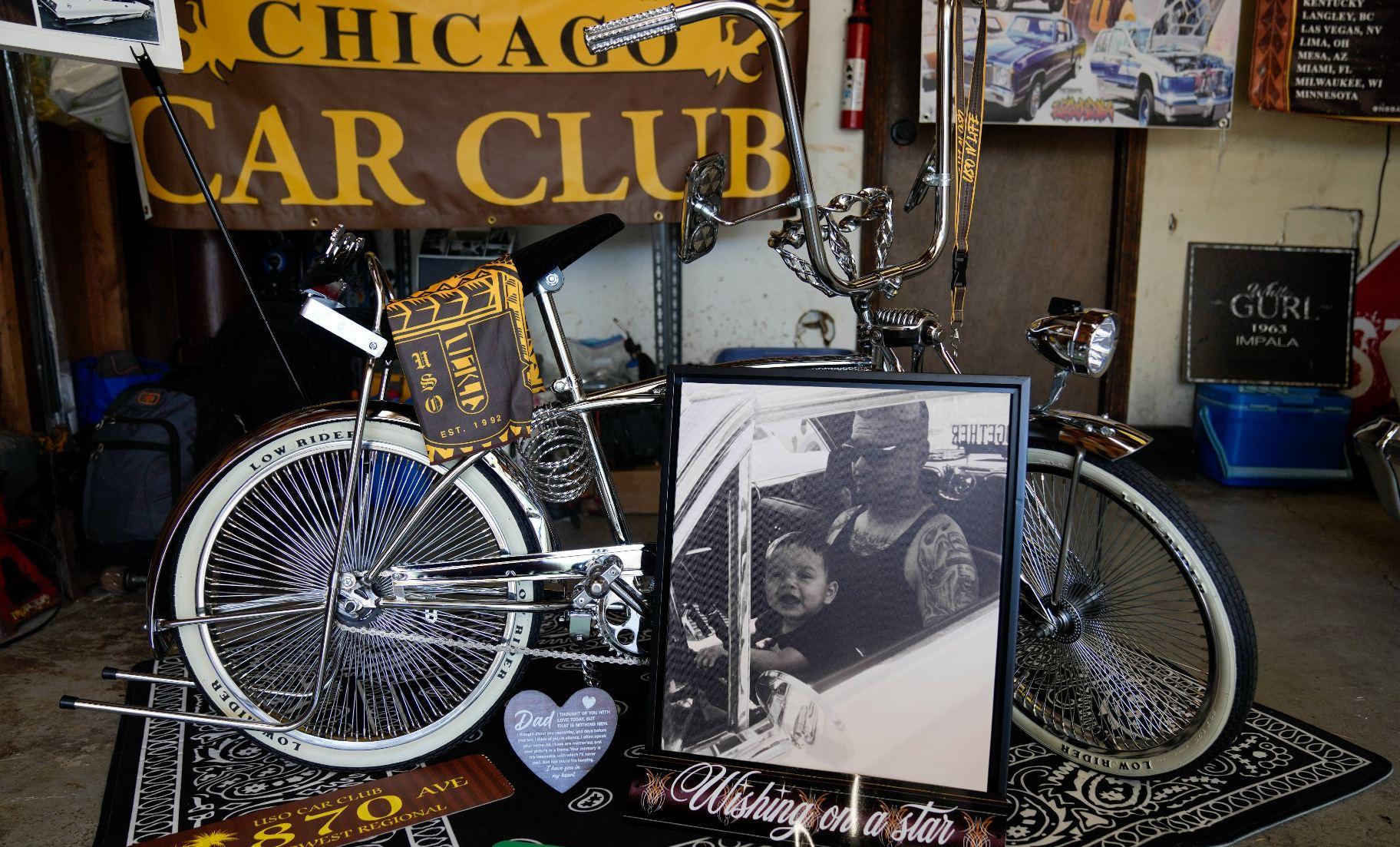 A photo of baby Daniel Marquez, now eight years old, sitting on his late father Alberto's lap inside their 1963 Chevy Impala lowrider car, is displayed with a custom chrome lowrider bike built by Daniel and family friends Saturday, Sept. 14, 2024, at his home in Frankfort, Ill. (AP Photo / Erin Hooley)