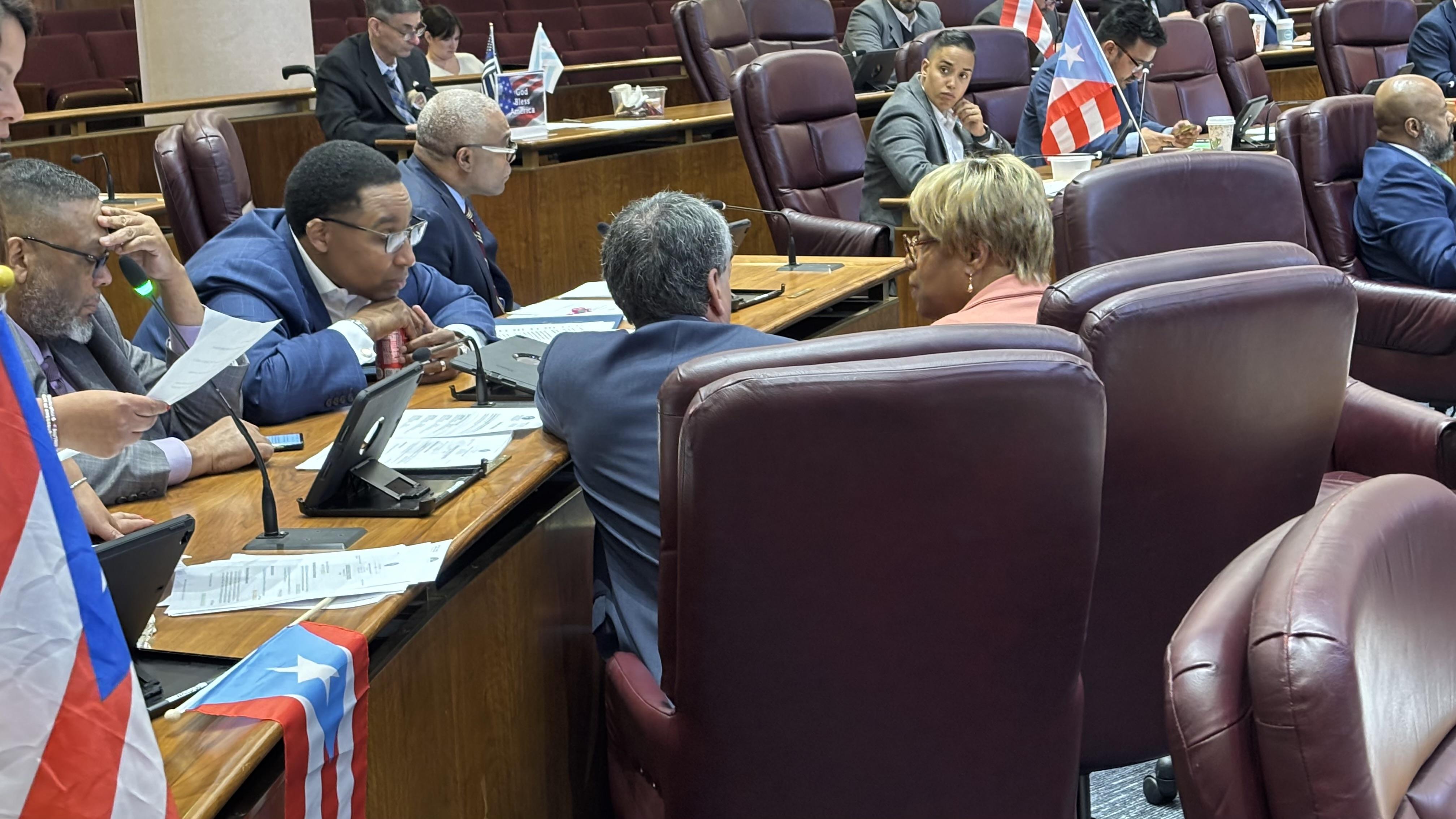 Ald. Jason Ervin, second from left, speaks with Ald. Pat Dowell, center, and Ald. Brian Hopkins shortly before blocking a vote on a proposal to allow the Chicago Police Department to declare so-called snap curfews. (Heather Cherone / WTTW News)