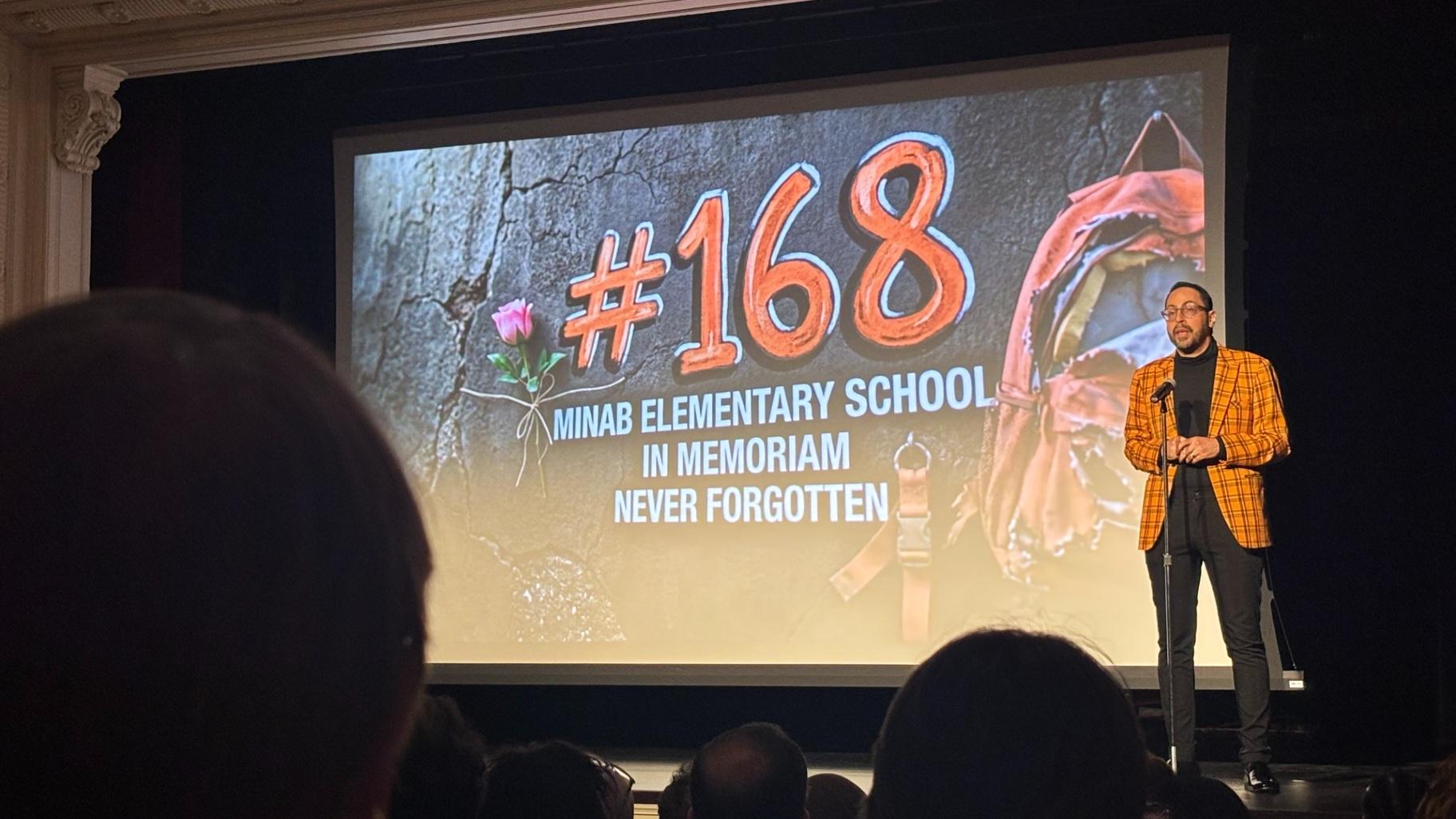 Ali Tarokh on stage at the “Voices Through Art” event, Aug. 20, 2026, at the Chicago History Museum. His presentation honored the lives lost from the U.S. missile strike that destroyed the Shajareh Tayyebeh Elementary School in Minab, Iran. (Shelby Hawkins / WTTW News)
